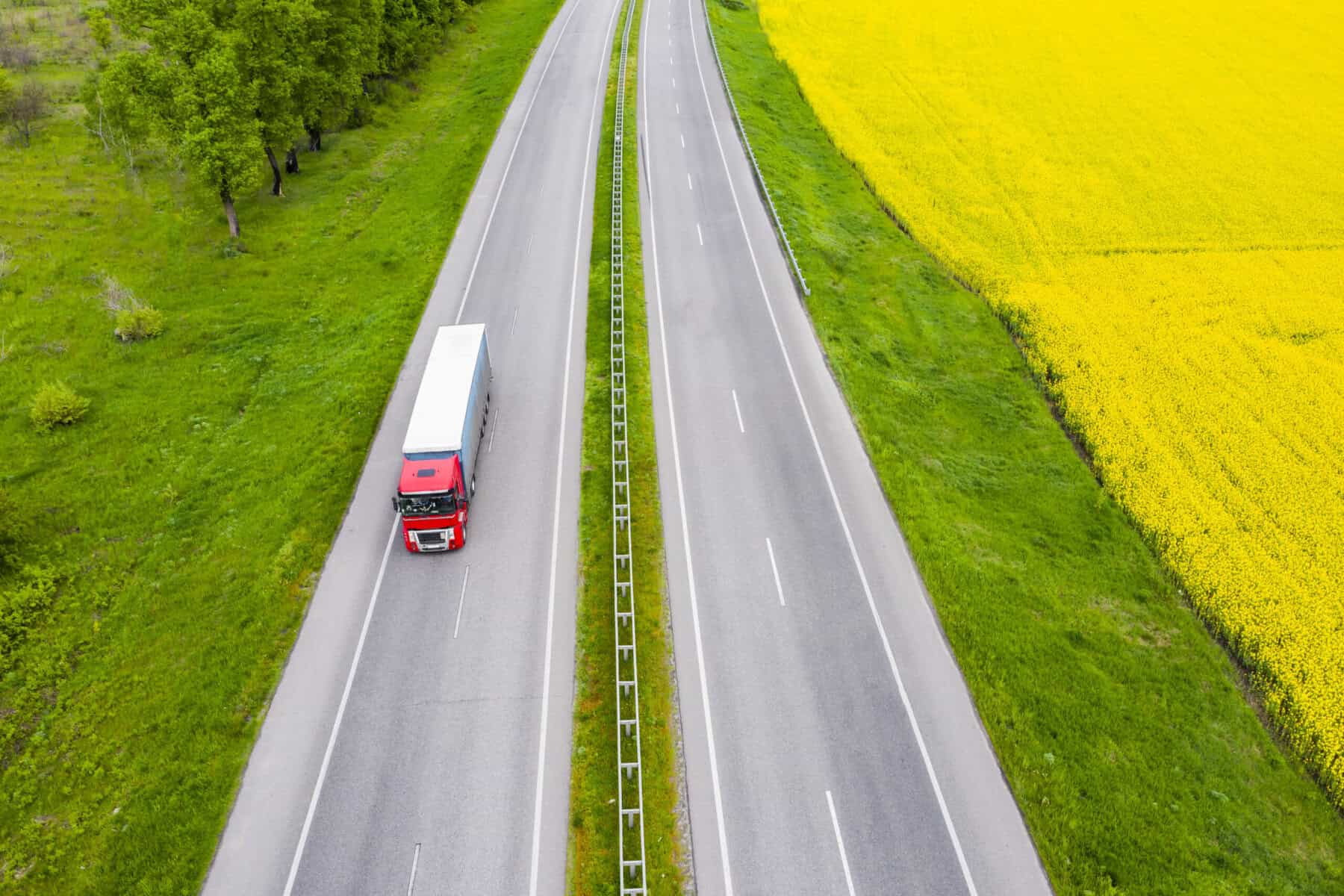 Red truck on empty highway near fields