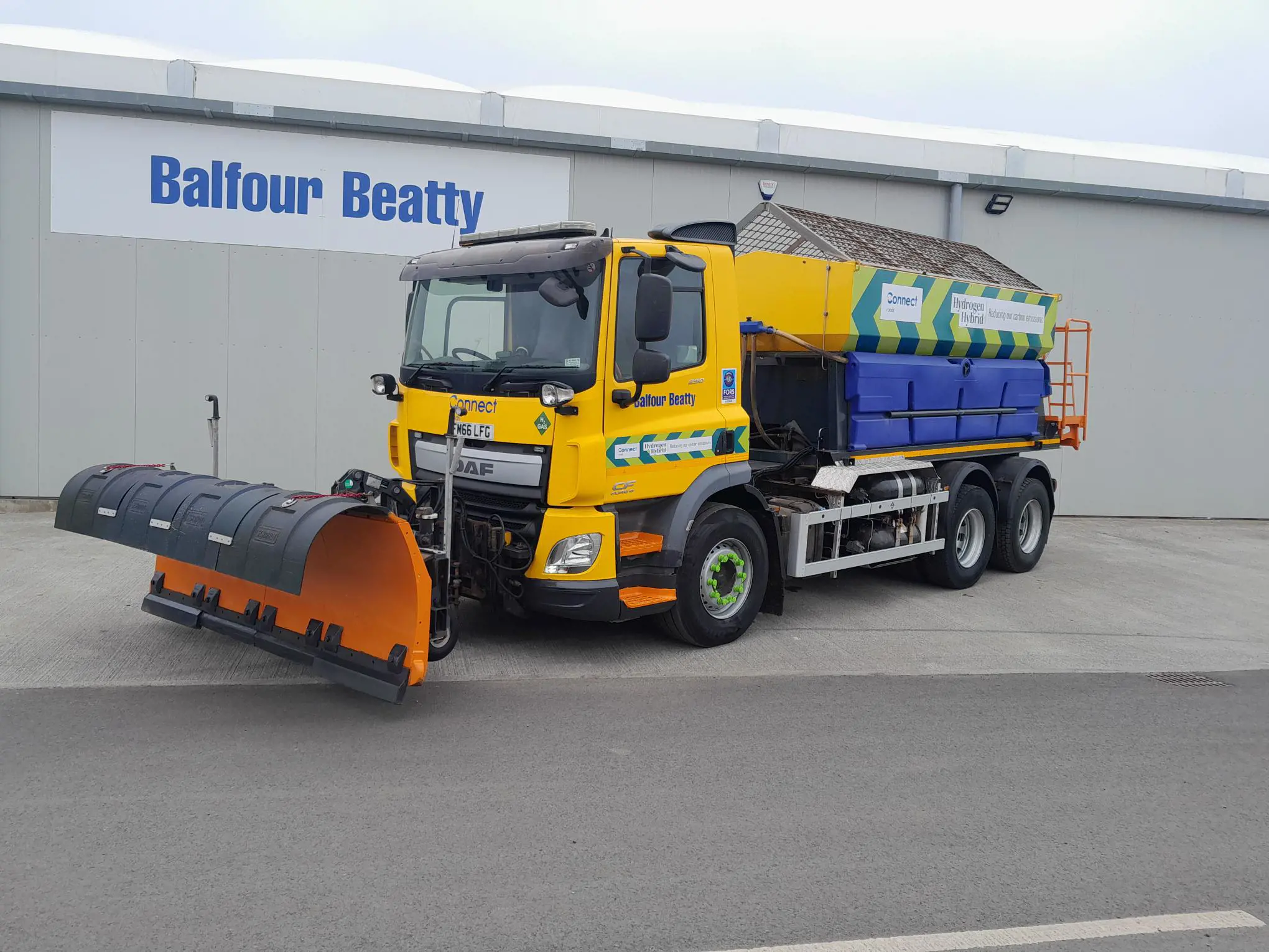 Yellow snow plow truck in front of building