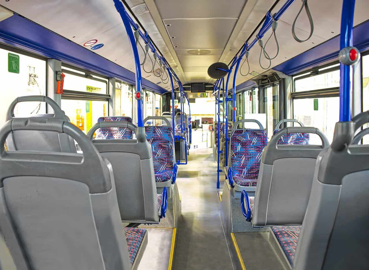 Interior of an empty city bus with blue seats.