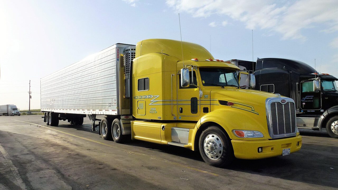 Yellow semi-truck parked at rest stop.